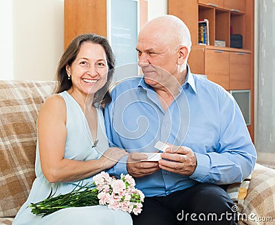 Senior man presenting smiling mature woman jewel