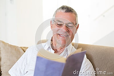 Senior man reading book on sofa