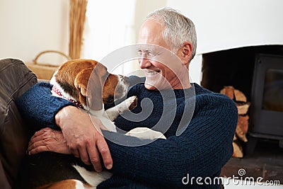 Senior Man Relaxing At Home With Pet Dog