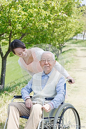 Senior man sitting on a wheelchair with caregiver