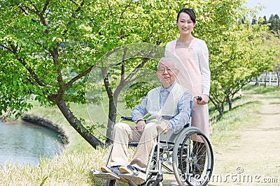 Senior man sitting on a wheelchair with caregiver