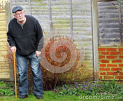 Senior man standing using a stick for support..