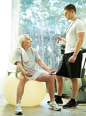 Senior man and trainer in a fitness club