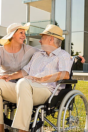 Senior man in wheelchair smiling on his wife