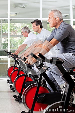 Senior men on spinning bikes in gym