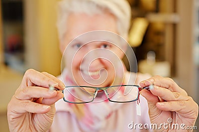 Senior optician holding glasses