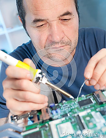 Senior tech fixes computer circuit board