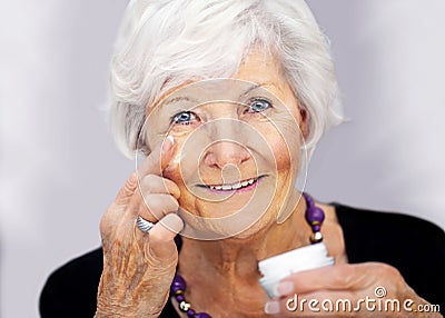 Senior woman applying cream on her face