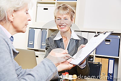 Senior woman in bank signing
