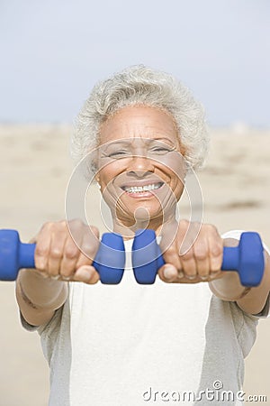 Senior Woman Exercising With Dumbbells On Beach