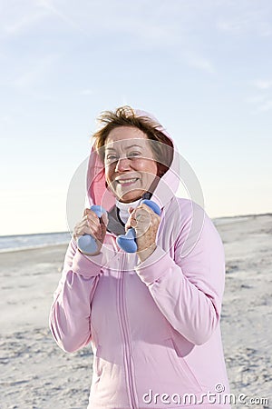 Senior woman exercising with hand weights on beach