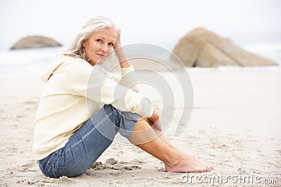 Senior Woman On Holiday Sitting On Winter Beach