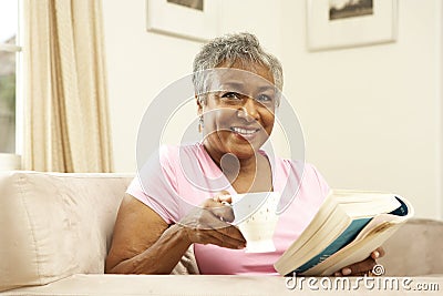 Senior Woman Reading Book With Drink