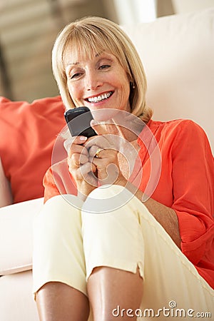 Senior Woman Relaxing On Sofa Sending Text Message