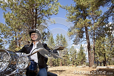Senior woman riding motorcycle through a forest