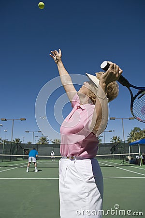 Senior Woman Serving Tennis Ball