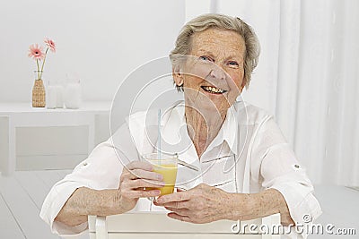 Senior Woman smilling while drinking Orange Juice