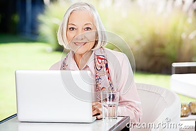 Senior Woman Using Laptop At Nursing Home Porch