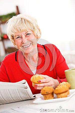 Seniors: Woman Having A Muffin and Newspaper