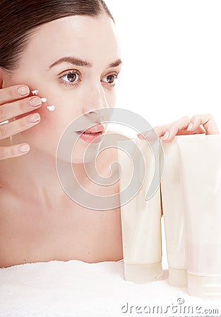 Sensual woman applying cosmetic cream treatment on her face.