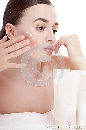 Sensual woman applying cosmetic cream treatment on her face.