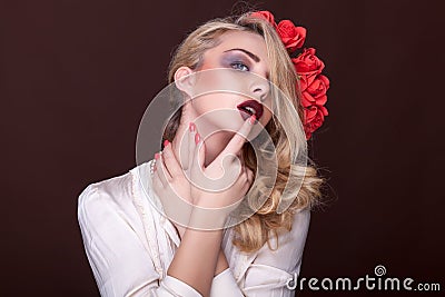 Sensual woman with finger on her lips and flowers in head