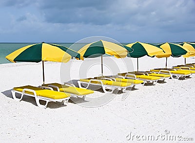Series of colorful lounge chairs on a white sand