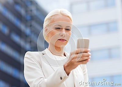 Serious businesswoman with smartphone outdoors