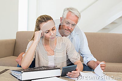 Serious couple calculating their bills at the couch