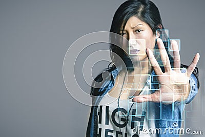 Serious mid adult woman touching futuristic computer screen over gray background