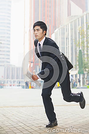 Serious, young businessman in a suit running in the business district in Beijing, China