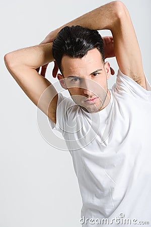 Serious young man standing against white background