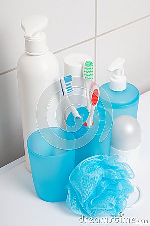 Set of blue hygiene supplies over tiled wall in bathroom