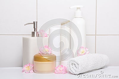 Set of white cosmetic bottles with flowers over tiled wall