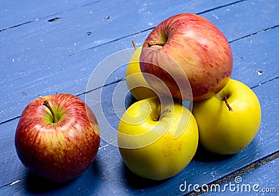 Several apples placed on a table painted blue