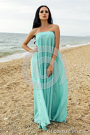 Sexy beautiful woman in elegant dress posing at beach