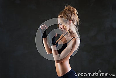 Sexy boxer woman making kick with boxing bandage