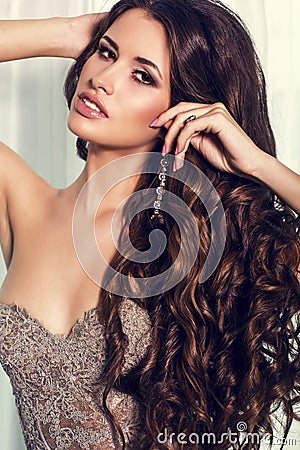 Sexy girl with luxurious curly dark hair in elegant beige dress