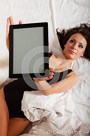 Sexy lazy girl lying with tablet touchpad on bed