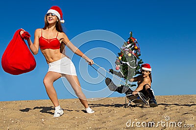 Sexy Santa helper pulling Santa at the beach