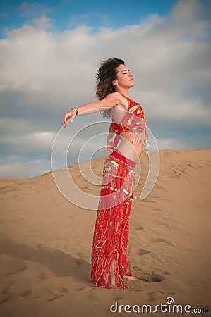 Sexy woman belly dancer arabian in desert dunes