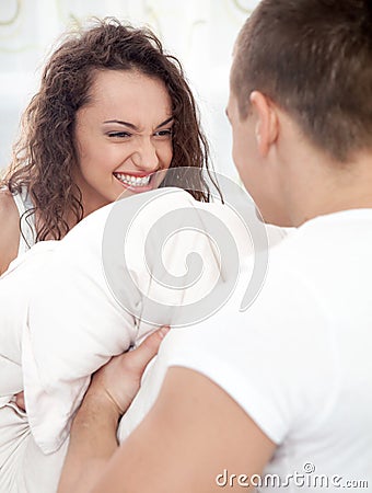 Sexy young couple having pillow fight in bedroom