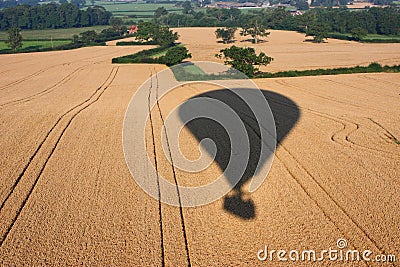 The Shadow of a hot air balloon flying over rural farmland