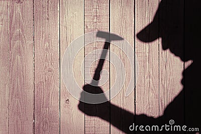 Shadow of a man with hammer on natural wooden background