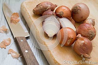 Shallots on wooden cutting board with knife