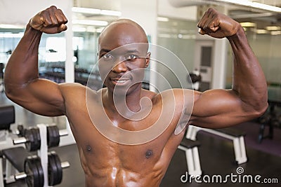 Shirtless muscular man flexing muscles in gym