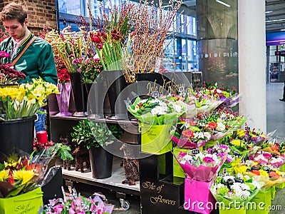 Shopper and bouquets at Isle of Flowers, St Pancras Station, London, UK.