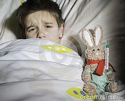 Sick child in bed with teddy bear