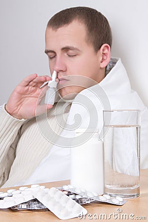 Sick man using nasal spray in living room