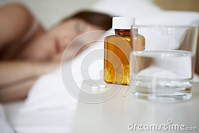 Sick Woman In Bed By Pills On Bedside Table